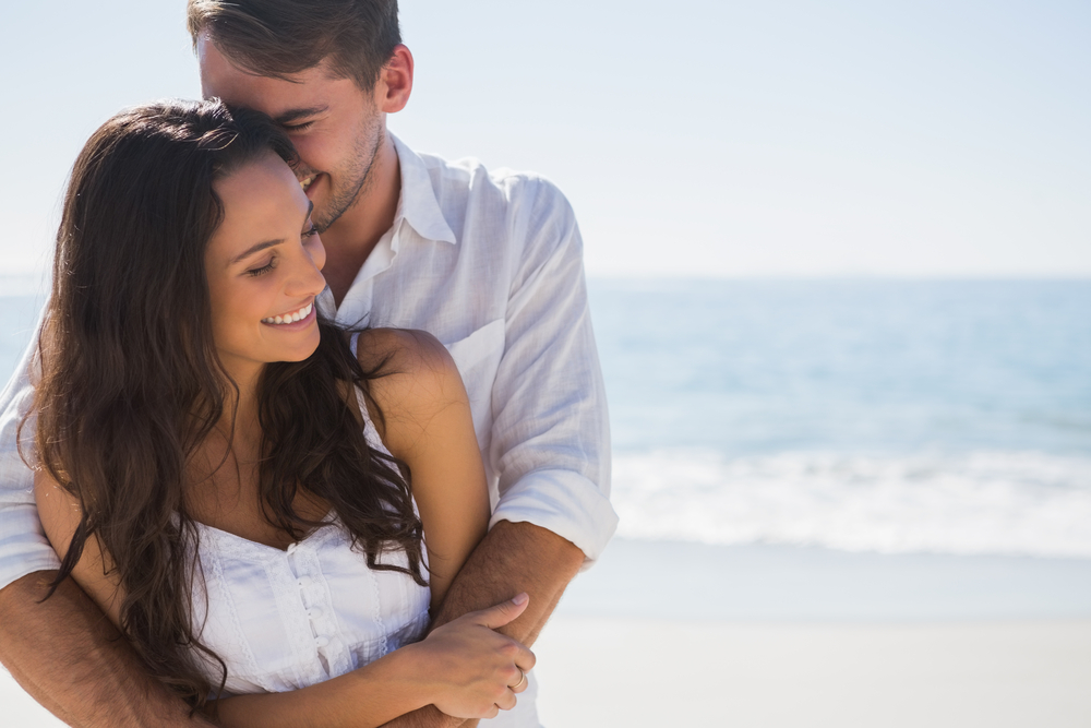 Happy couple walking on the beach together, enjoying a stronger relationship